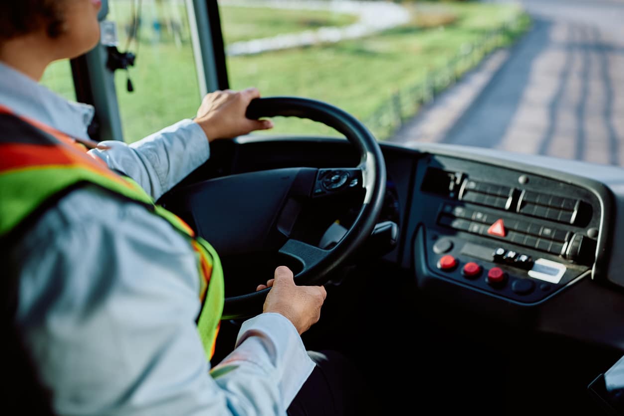 Close up of female driver behind the steering wheel of a bus.