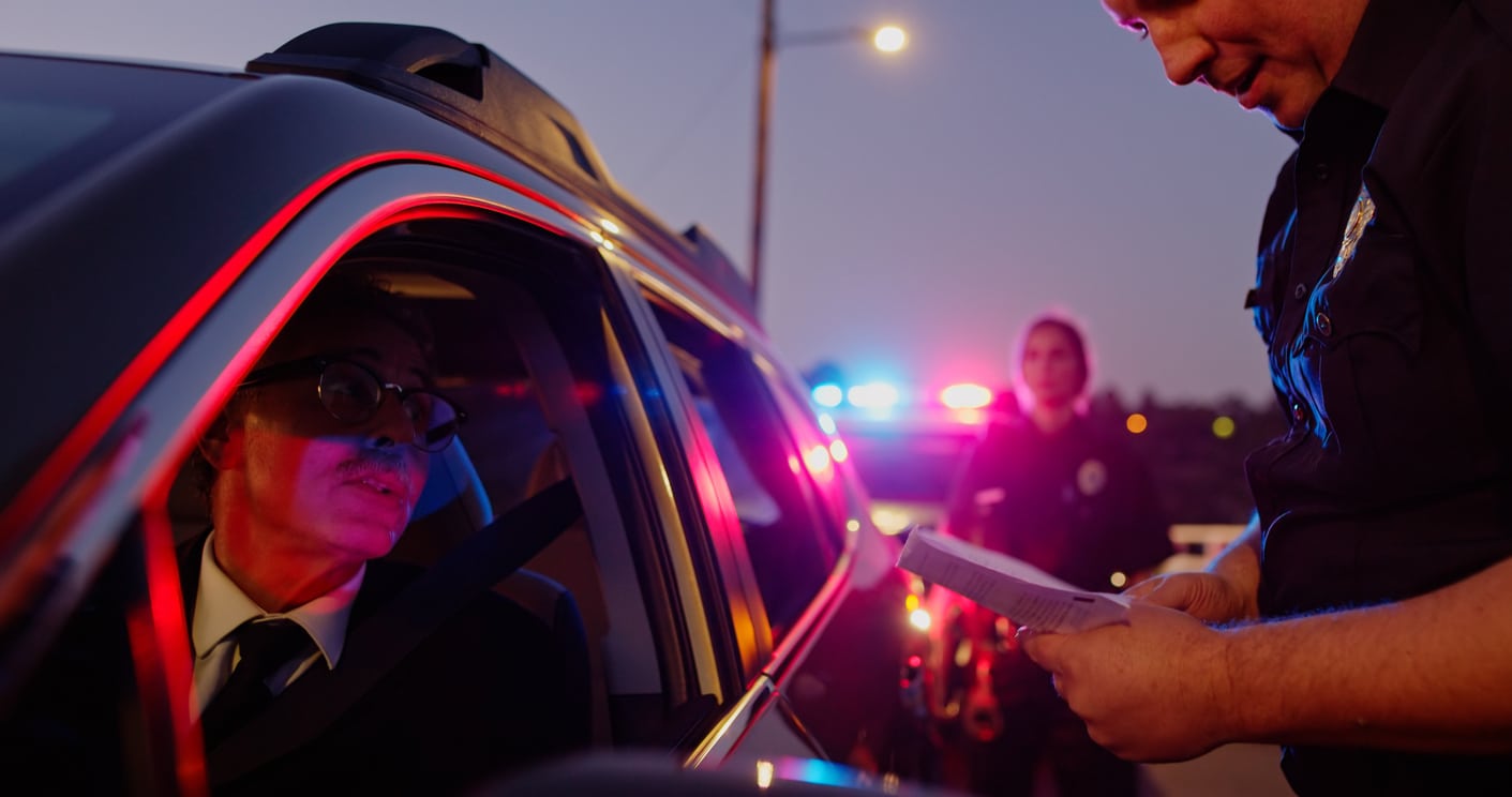 Police Officer Checking a Senior Driver's Documents During Traffic Stop at Dusk