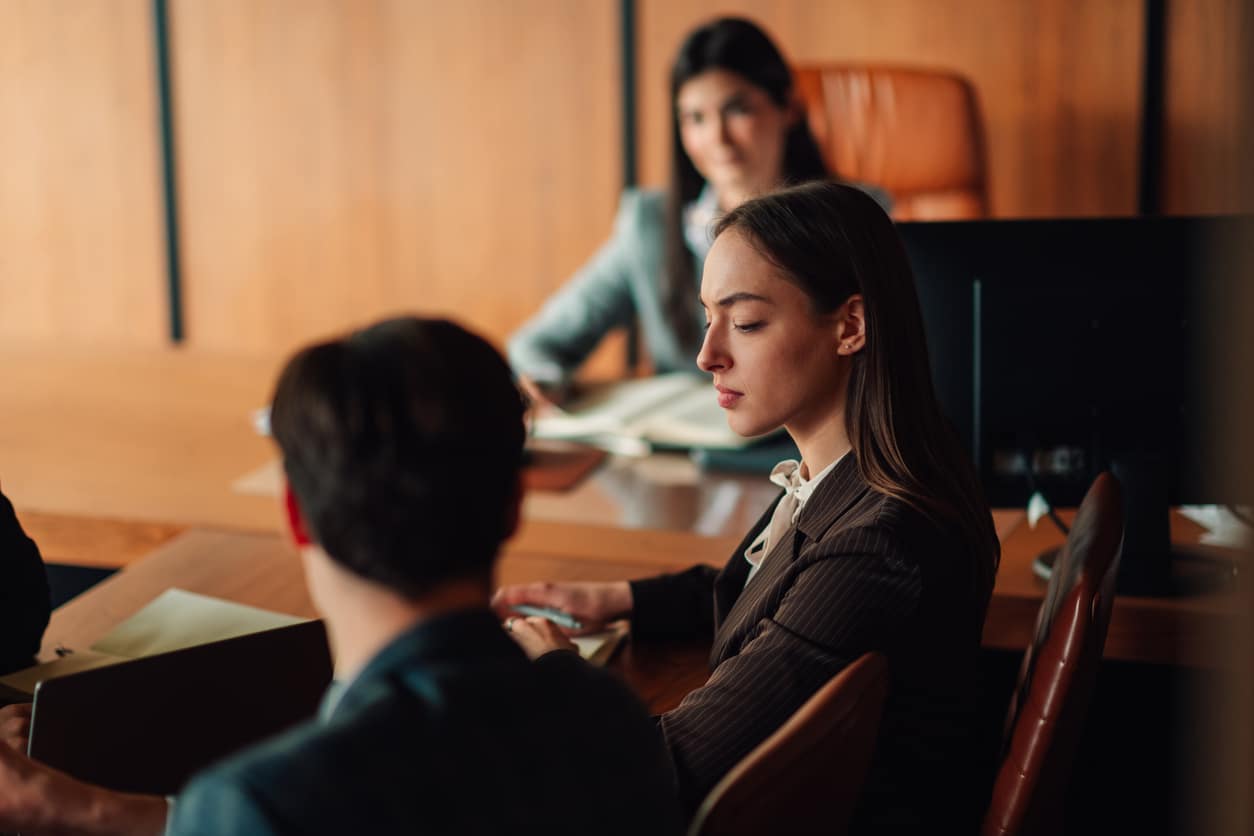 Young adult woman attending a business meeting or legal proceeding, focused and listening intently in conference room