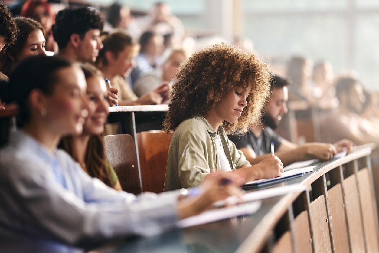 Young female student writing on a class in amphitheater.